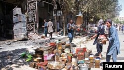 FILE - Afghan shopkeepers try to recover items from burning shops after a Taliban attack in Ghazni city, Afghanistan, Aug. 14, 2018. Afghan officials allege sanctuaries in Pakistan have enabled the Taliban to sustain and expand their insurgent activities. Islamabad calls these charges baseless.