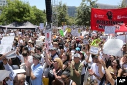 People hold signs as they participate in the "Families Belong Together: Freedom for Immigrants" march, June 30, 2018, in Los Angeles.