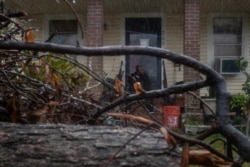A local resident is framed by debris from Hurricane Laura, as he watches the arrival of Hurricane Delta from his doorsteps in Lake Charles, Louisiana, Oct. 9, 2020.