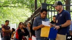 FILE - An Immigration and Customs Enforcement official gives directions to a person outside the building that houses ICE and the Atlanta Immigration Court, in Atlanta, Georgia, June 12, 2019.