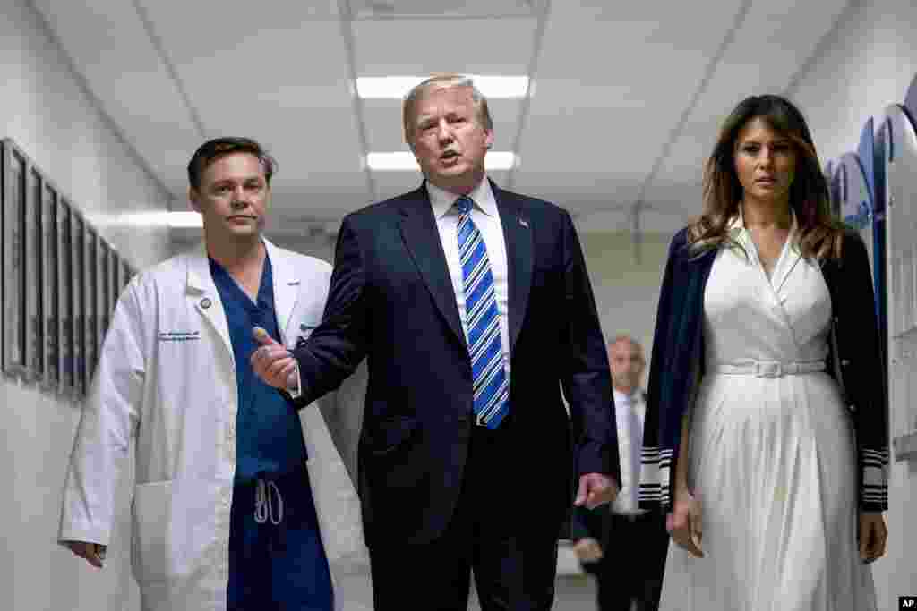 President Donald Trump, center, accompanied by first lady Melania Trump, right, and Dr. Igor Nichiporenko, left, speak to reporters while visiting with medical staff and victims of a mass shooting at a local school in Pompano Beach, Fla., Feb. 16, 2018.