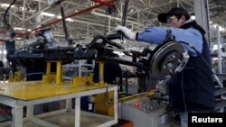 FILE - An employee works on an assembly line producing electronic cars at a factory of Beijing Electric Vehicle, funded by BAIC Group, in Beijing, China, Jan. 18, 2016. 