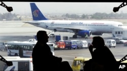 FILE - Tourists wait for their flight, as an Egyptair plane is seen, background, at a waiting hall in Cairo's international airport in Egypt. 