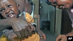 A Sierra Leonean maternal and child health aide administers a vaccine to a child in the village of Sembehun, outside the town of Bo, in the southeast region of the West African country, May 2011