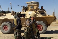 FILE - Afghan security forces stand near an armored vehicle during fighting between Afghan security forces and Taliban fighters in the Busharan area on the outskirts of Lashkar Gah, the capital of Helmand province, May 5, 2021.
