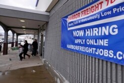 FILE - A 'Now Hiring' sign hangs on the front wall of a Harbor Freight Tools store in Manchester, N.H., Dec. 10, 2020.