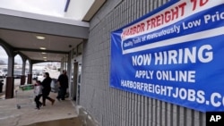 FILE - A 'Now Hiring' sign hangs on the front wall of a Harbor Freight Tools store in Manchester, New Hampshire, Dec. 10, 2020.
