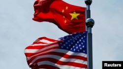 FILE - A Chinese and U.S. flag flutter in Shanghai, China, July 30, 2019.