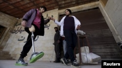 Khamis (R), 24, helps a man with an amputated leg walk using an artificial limb in the rebel-controlled area of Maaret al-Numan town in Idlib province, Syria, March 20, 2016.