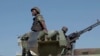 FILE - In this image made from video, a Mozambican soldier rides on an armored vehicle at the airport in Mocimboa da Praia, Cabo Delgado province, Aug. 9, 2021.