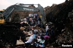 Rescue workers watch as excavators dig into a pile of garbage in search of missing people following a landslide when a mound of trash collapsed on an informal settlement at the Koshe garbage dump in Ethiopia's capital Addis Ababa, March 13, 2017.