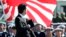 Thủ tướng Nhật Bản Shinzo Abe duyệt hàng quân danh dự của Lực lượng Phòng vệ Nhật Bản (SDF) tại Căn cứ Asaka, phía bắc Tokyo. Kế hoạch nới rộng sứ mạng của Lực lượng Tự vệ Nhật Bản của ông Abe vấp phải sự chống đối của phe chủ hoà trong nước và những sự chỉ trích của các nước láng giềng, đặc biệt là Trung Quốc.