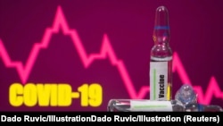 A test tube labelled with the Vaccine is seen in front of Covid-19 and stock graph logo in this illustration taken.