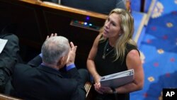 FILE - Rep. Marjorie Taylor Greene, right, speaks with fellow Republicans in the House chamber, at the Capitol in Washington, June 30, 2021. 