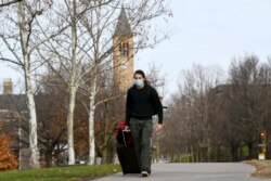 Cornell University sophomore, Kieran Adams, wheels his luggage through the university's campus in Ithaca, NY, Dec. 16, 2021, en route to go home after the university abruptly shut down all campus activities.