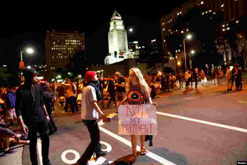 A female demonstrator holds a sign reading "Not My President" after retreating off the Hollywood 101 Freeway during a protest against the election of Republican Donald Trump as President of the United States in Los Angeles, California, U.S. Nov. 10, 2016.