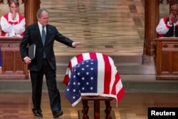 An emotional former President George W. Bush touches the flag-draped casket of his father, former President George H.W. Bush, after speaking during his State Funeral at the National Cathedral, Dec. 5, 2018, in Washington.