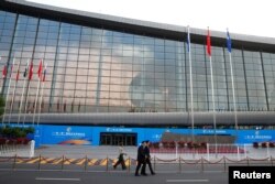 People walk past the China National Convention Center, a venue of the upcoming Belt and Road Forum in Beijing, May 12, 2017.