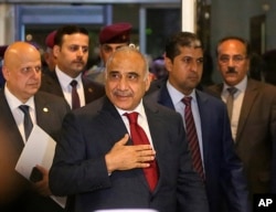 FILE - Prime Minister-designate Adel Abdul-Mahdi, center, arrives to the parliament building, in the heavily guarded Green Zone, in Baghdad, Iraq, Oct. 24, 2018.