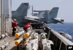 FILE - U.S. Navy crewmen from the U.S. Navy aircraft carrier USS Carl Vinson (CVN 70) prepare to load missiles to F-18 fighter jets prior to a routine patrol off the disputed South China Sea.