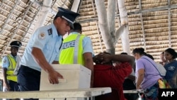 A police officer handles a ballot box as voters gather at a polling station during Kiribati's national elections in Tarawa on Aug. 14, 2024.