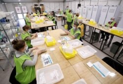 Medical workers prepare doses of Oxford/AstraZeneca's COVID-19 vaccine at a vaccination center in Antwerp, Belgium, March 18, 2021.