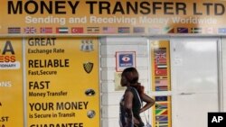 A woman looks at the closed doors of a money-transfer service in Nairobi, Kenya Wednesday, April 8, 2015. The Kenya government said Wednesday that it was freezing the accounts of a list of companies and individuals identified because of suspicious transac