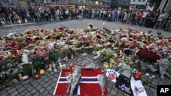 People mourn the victims of the shooting spree on an island and a bomb attack in the Norwegian capital, around an improvised shrine in Oslo, July 23, 2011