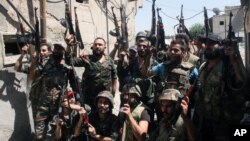 Syrian soldiers cheer after battling with rebels during a tour for journalists organized by the Syrian Information Ministry in the Damascus suburb of Jobar, Syria, July 14, 2013.