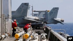 FILE - U.S. Navy crewmen from the U.S. Navy aircraft carrier USS Carl Vinson (CVN 70) prepare to load missiles to F-18 fighter jets prior to a routine patrol off the South China Sea, March 3, 2017. 