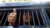 FILE - Myanmar activist Moe Thway gives a thumbs-up sign from a police truck as he is taken to a township court with other activists, in Yangon, Myanmar, Nov 22, 2013.