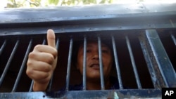 FILE - Myanmar activist Moe Thway gives a thumbs-up sign from a police truck as he is taken to a township court with other activists, in Yangon, Myanmar, Nov 22, 2013.