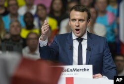 FILE - Supporters of French presidential candidate Emmanuel Macron hold placards as he speaks during a campagin rally in Lyon, central France, Feb. 4, 2017. Macron is among Le Pen's challengers.