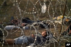 Afghan refugees sleep next to razor-wire barrier at the Serbian side of Hungary's border fence with Serbia, in Asotthalom, southern Hungary, Sept. 17, 2015.