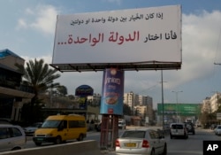 FILE - Motorists pass a banner supporting the creation of a single state for Israelis and Palestinians that reads in Arabic: "If I had to choose between one state and two states, I would choose the one state," in the West Bank city of Ramallah, Feb. 23, 2017.