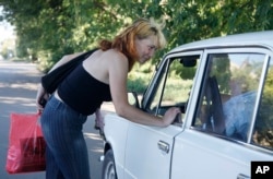 FILE - A sex worker talks to a driver on a roadside in the city of Cherkassy, 200 kilometers (124 miles) southeast of the Ukrainian capital Kyiv, July 16, 2010.