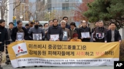 Victims of Japan's forced labor and their family members arrive at the Supreme Court in Seoul, South Korea, Nov. 29, 2018. The sign reads " Mitsubishi Heavy Industries apologize and compensate victims."