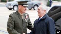 FILE - Chairman of the Joint Chiefs Gen. Joseph Dunford, left, shakes hands with Secretary of Defense James Mattis as Mattis arrives at the Pentagon in Washington, Jan. 21, 2017.