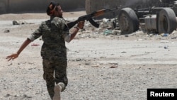 A Kurdish fighter from the People's Protection Units (YPG) fires his rifle at Islamic State militants as he runs across a street in Raqqa, Syria, July 3, 2017.