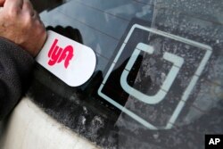 FILE - A Lyft logo is installed on a Lyft driver's car next to an Uber sticker in Pittsburgh, Jan. 31, 2018. The “gig” economy might not be the new frontier for America’s workforce after all.