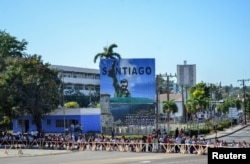 Students wait in line in front of an image of Cuba's late President Fidel Castro before paying tribute to Castro in Santiago de Cuba, Nov. 28, 2016.