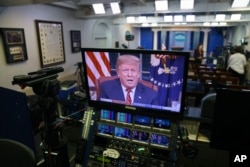 President Donald Trump is seen on monitors in the briefing room of the White House, as he gives a prime-time address in the Oval Office, Jan. 8, 2019.