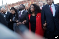 Oprah Winfrey locks arms with David Oyelowo, left, who portrays Martin Luther King Jr. in the movie "Selma," Ava DuVernay, the director of "Selma" and rapper Common, far left, as they march to the Edmund Pettus Bridge in honor of Martin Luther King Jr., i