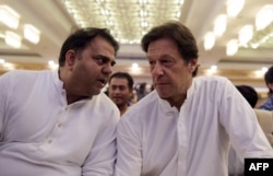 Pakistani cricketer-turned-politician and head of the Pakistan Tehreek-i-Insaf Imran Khan,r ight, speaks with his party spokesperson Fawad Chaudhry before presenting their party manifesto for the forthcoming general election in Islamabad on July 9, 2018.