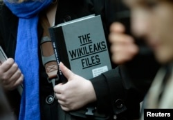 A supporter of WikiLeaks founder julian Assange holds a copy of The WikiLeaks Files outside the Ecuadorian embassy in central London, Britain Feb. 5, 2016.