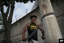 In this May 27, 2016 photo, Popole Misenga, a refugee and judo athlete from the Democratic Republic of Congo, uses a judo black belt attached to a street light pole to trains near his home in Rio de Janeiro, Brazil.