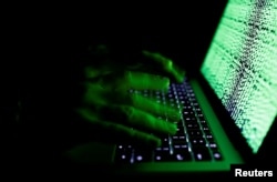 A man types on a computer keyboard in front of the displayed cyber code in this illustration picture taken on March 1, 2017.