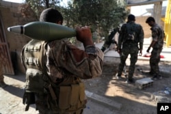 FILE - U.S.-backed Syrian Democratic Forces fighters, prepare to fire a mortar shell, at one of the front lines, in Raqqa city, northeast Syria, July 27, 2017.