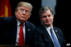 FILE - President Donald Trump sits with FBI Director Christopher Wray during the FBI National Academy graduation ceremony in Quantico, Va.