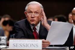 FILE - Attorney General Jeff Sessions reads from a statute about his recusal while testifying on Capitol Hill in Washington, June 13, 2017, before a Senate Intelligence Committee hearing.